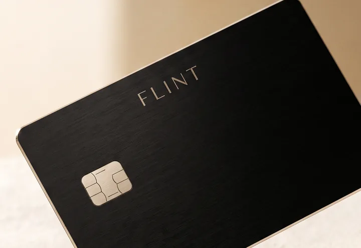 The FLINT metal card standing on a pale plaster surface.